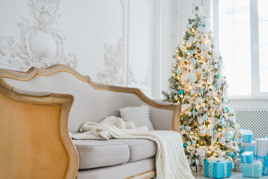 Calm image of interior luxury home living room decorated christmas tree and gifts, sofa covered with blanket. Selective focus