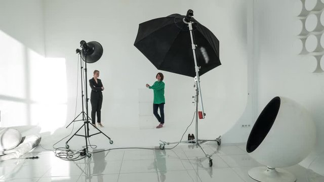 Timelapse shot of professional photographer and woman model having photo shoot in studio