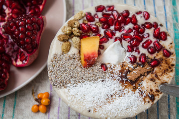 vegan banana smoothie with pomegranate, mulberry, coconut, Chia, carob. Raw fruit energy food. Detof and healthy breakfast bowl. 