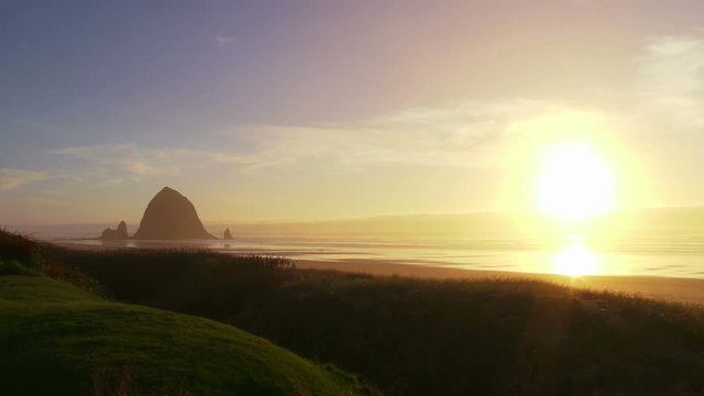 Man at Pacific Ocean near Cannon Beach looks out to sea as sun sets on beautiful day.