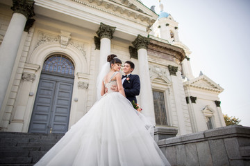 Obraz premium Wedding bride and groom, happy young couple hugging near the place of wedding ceremony