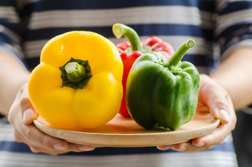 Fresh bell pepper on wooden plate holding by hand,healthy food