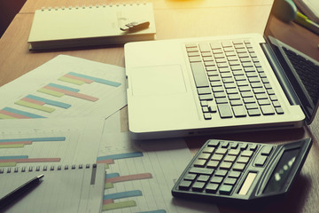 Laptop, calculator with financial documents on wooden table