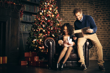 Naklejka na ściany i meble Young family in living room on Christmas night