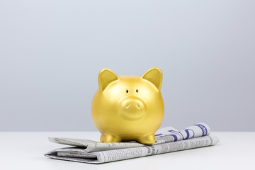 gold piggy bank on newspaper