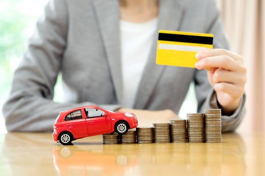 Businesswoman hand hold credit card, a toy car and a stack of co