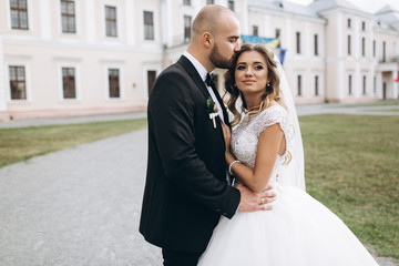 Fototapeta premium Stylish bride and bearded muscular groom posing on the wedding