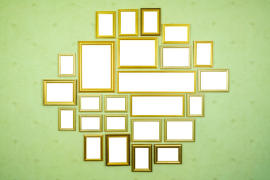Many empty golden wooden frames with copy space on green wallpapered wall.