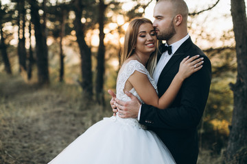 Stylish bride and bearded muscular groom posing on the wedding