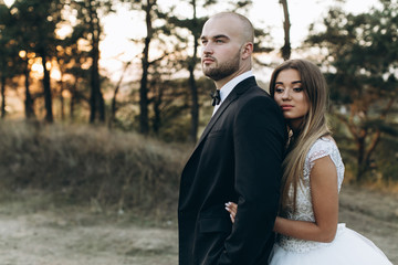 Fototapeta premium Stylish bride and bearded muscular groom posing on the wedding