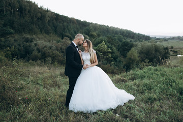 Stylish bride and bearded muscular groom posing on the wedding