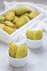 Homemade matcha green tea madeleines on the table and in wooden tray, vertical