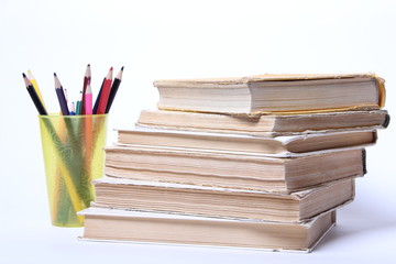 stack of old books. pencils in a glass