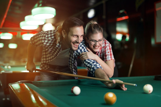 Couple playing billiards together