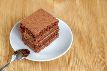 Piece of chocolate cake in white plate on wooden table