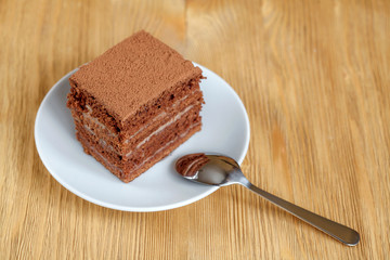 Piece of chocolate cake in white plate on wooden table