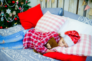 Little girl in red hat sleeping before Christmas