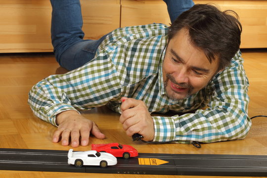 Mann startet Spielzeugautos auf Autorennbahn