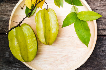 green fruit with leaves. On a wooden dish and  table. copy space for text