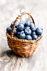 blueberries  in wicker basket isolated on rustic wooden backgrou