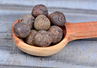 Wooden spoon with allspice on table