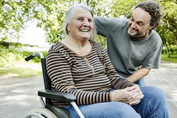 Sohn spricht mit seiner dementen Mutter im Rollstuhl