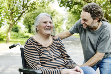 Sohn spricht mit seiner dementen Mutter im Rollstuhl