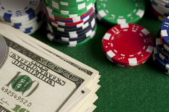 Dollar bills and poker chips on green table