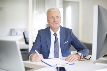 Senior professional man at work. Close-up of a senior financial manager sitting at his workstation...