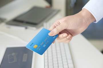 Online banking. Close-up shot of a young businesswoman sitting in the office in front of computer and holding credit card.