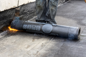 worker while burning the waterproof membrane on a roof