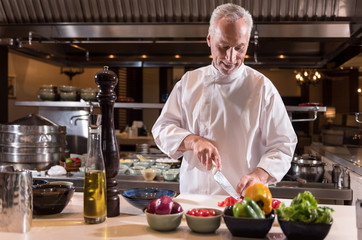 Delighted chef cutting paper in the kitchen of the restaurant
