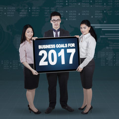 Business people holding billboard with 2017