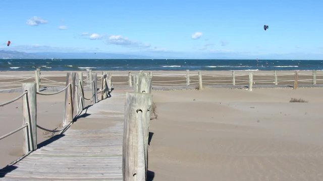 Pasarela en la playa con kitesurfistas al fondo / Walkway on the beach with kite surfers in the background