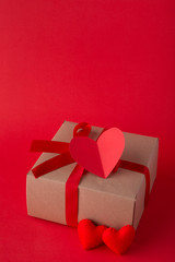 Gift box and red heart shapes on red background