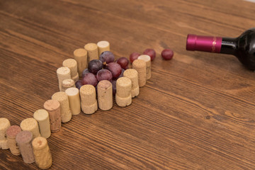 Glass made with cork wine and grapes inside on wood background