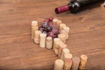 Glass made with cork wine and grapes inside on wood background