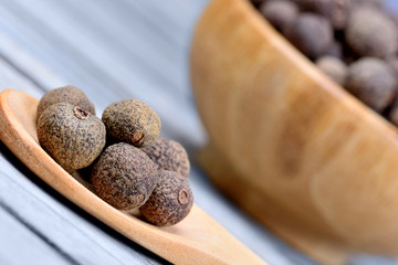 Allspice in a wooden spoon and bowl
