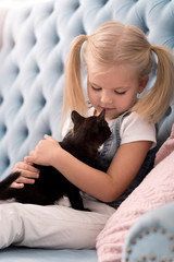 Cute sweet girl holding a black kitten