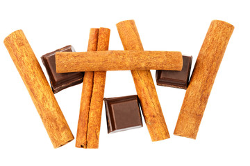 Dark chocolate cubes and cinnamon sticks isolated on white background, top view.