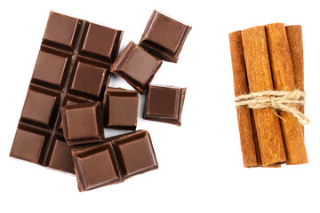 Dark chocolate bar, cubes and cinnamon sticks isolated on white background, top view.