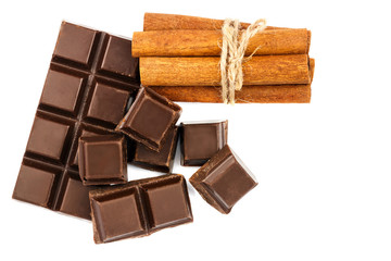 Dark chocolate bar, cubes and cinnamon sticks isolated on white background, top view.