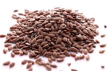 Flax seeds lay on a white background in a pile
