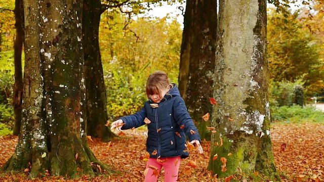 enfant jouant avec les feuilles en automne