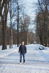 Fototapeta na wymiar Young handsome smiling man stands in a city Park on a clear winter day