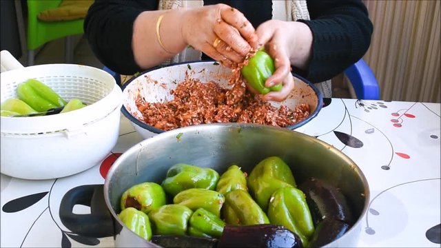 Turkish woman making Dolma - Traditional Turkish food. Pepper and eggplant stuffed with rice and minced meat. 