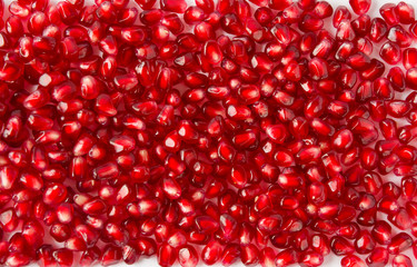Background made of red pomegranate seeds. The scattered red grains of a pomegranate.
