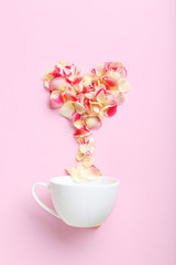 Rose petals and white cup on a pink background