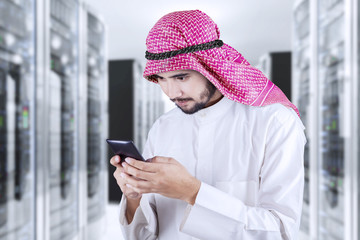 Arabic person with smartphone in server room