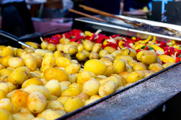 Fresh trout fish, baked potatoes and colorful grilled vegetables in a large baking pan in a summer festival.